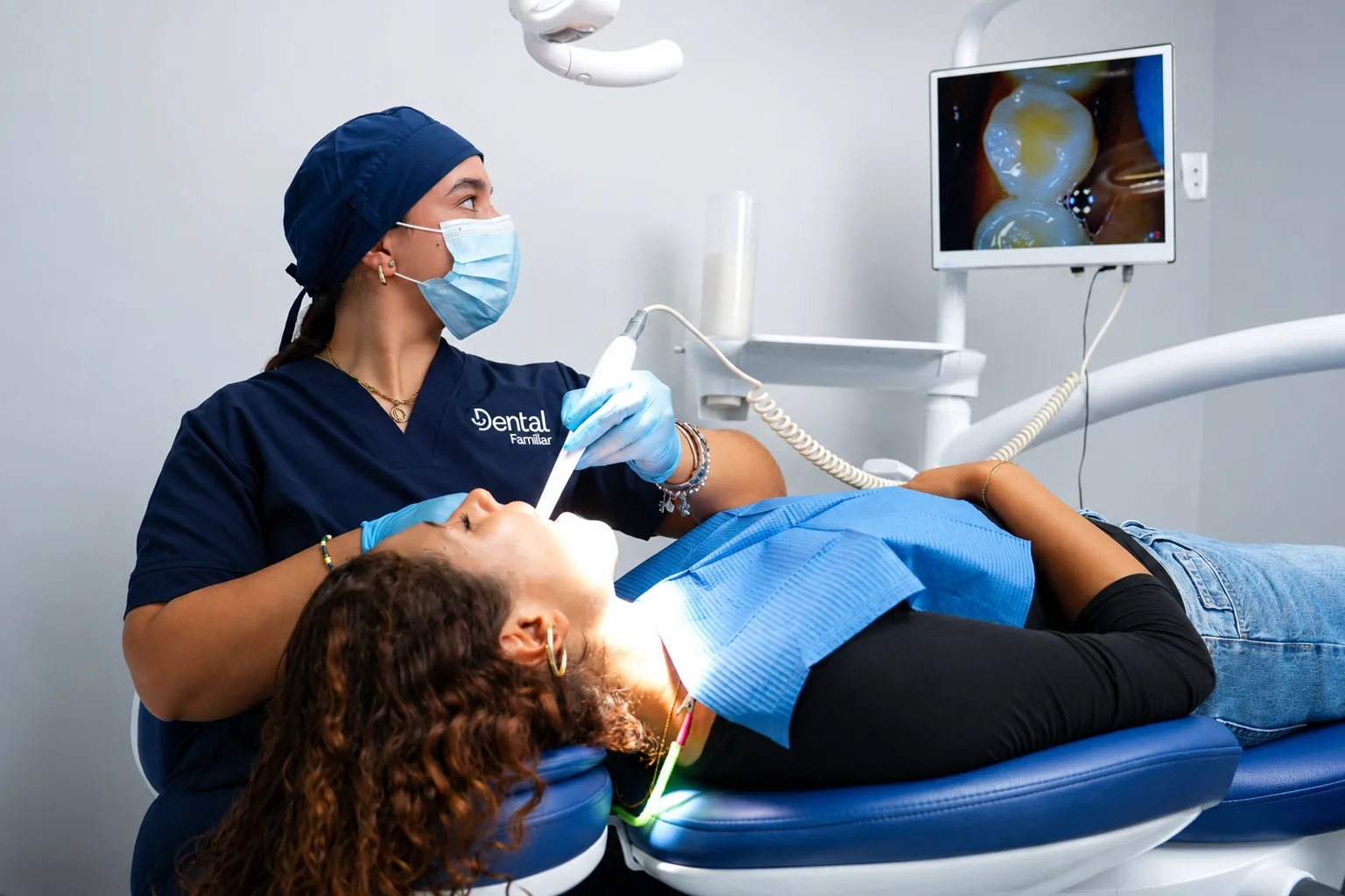Dentista de Dental Familiar revisando a una paciente con cámara intraoral, con la imagen en el monitor